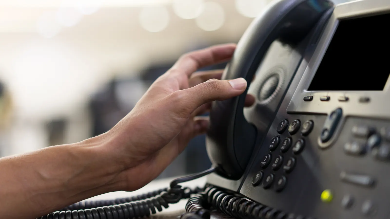 Main décrochant le téléphone d'un bureau pour organiser un remplacement