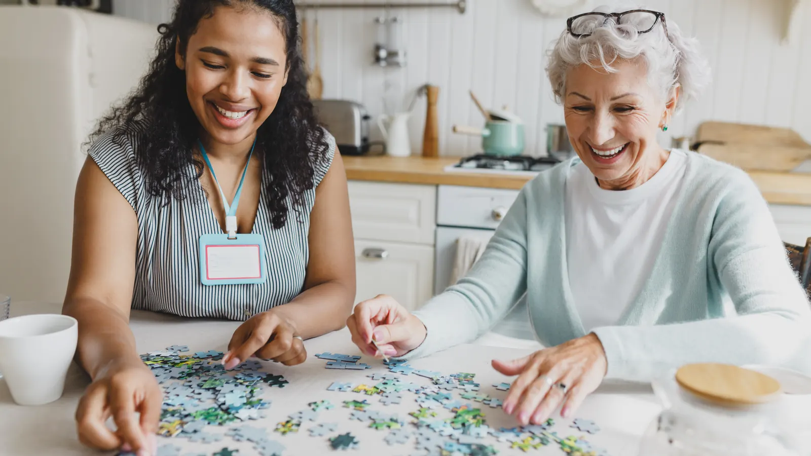 Auxiliaire de vie faisant un puzzle avec une dame âgée